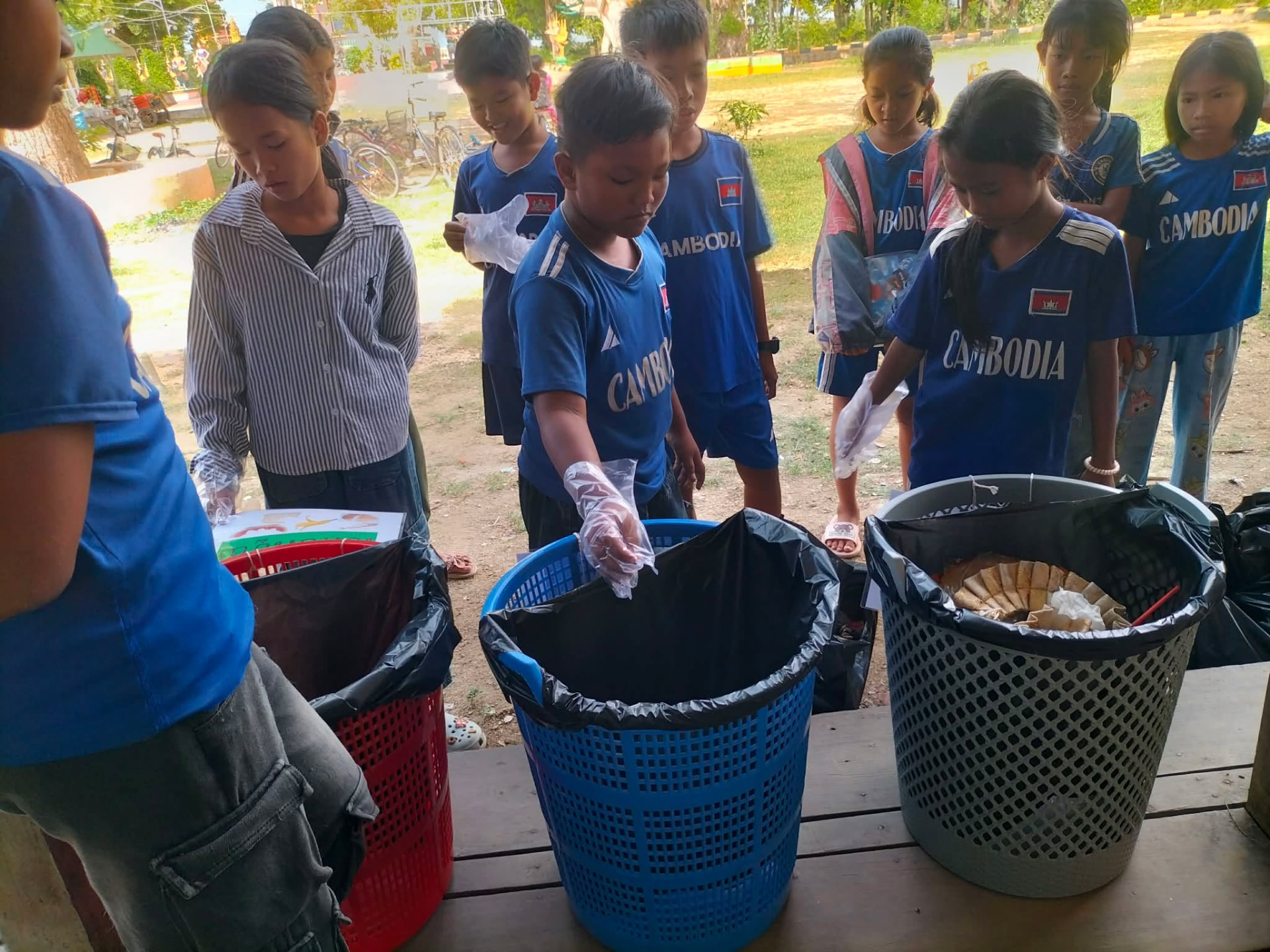 Pupils sorting waste into three labelled bins during the recycling project